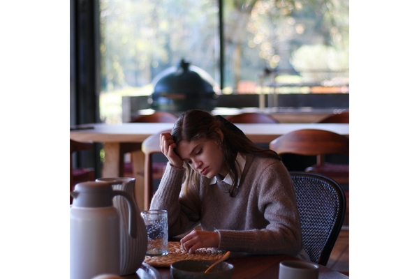 Image A young woman looks sad while sitting a table